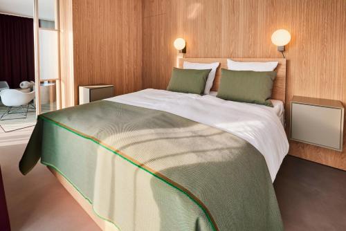 a bedroom with a large bed with green pillows at Kirk Suites in Vejle