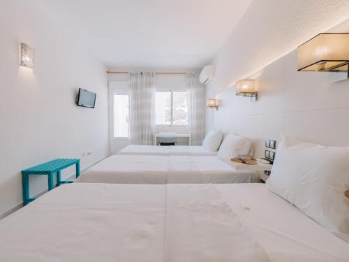 Habitación blanca con 4 camas y ventana en Hostal Las Gaviotas del Cabo, en San José