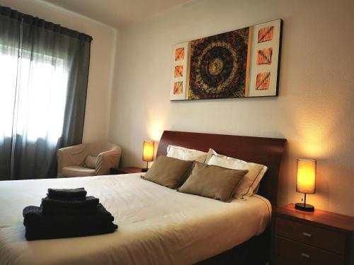 a bedroom with a bed with two lamps and a chair at Gustavo's Place in Sines