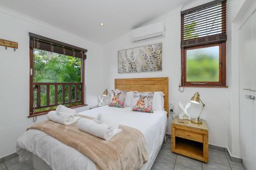 a white bedroom with a bed and a window at San Lameer Villa 2908 - 3 Bedroom Superior - 6 pax - San Lameer Rentals Agency in Southbroom