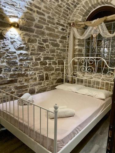 Cama en habitación con pared de ladrillo en Cozy stone built apartment in Nénita!, en Chios