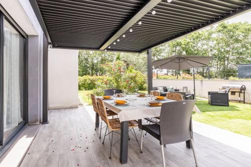 une terrasse avec une table, des chaises et un parasol dans l'établissement Villa des rives du Tarn avec jacuzzi, à Montans