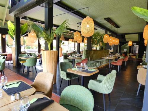 un ristorante con tavoli, sedie e piante di Hôtel Be Guest Limoges Sud ex Black & Green a Limoges