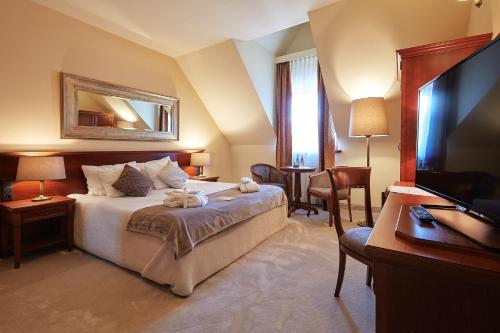 a bedroom with a bed and a flat screen tv at Grand Hotel Stamary in Zakopane