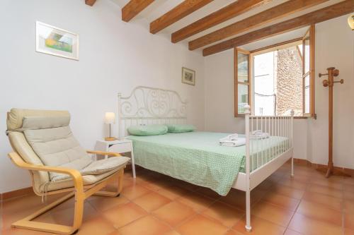 a bedroom with a bed and a chair and a window at Ca's Pobres in Sóller