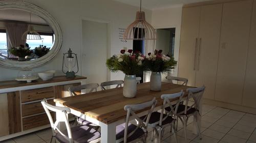 a dining room table with chairs and a mirror at Mafari Beach House in Hermanus