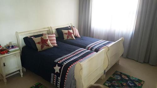 a bedroom with a bed with pillows and a window at Mafari Beach House in Hermanus