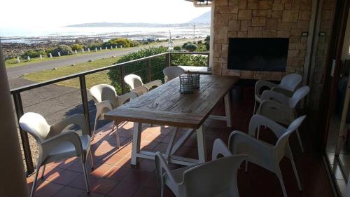 a wooden table and chairs on a balcony with a television at Mafari Beach House in Hermanus