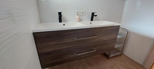 baño con lavabo blanco y armario de madera en Appartements Haus Bergland, en Sankt Martin am Tennengebirge