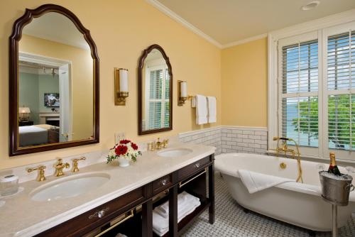 uma casa de banho com 2 lavatórios, uma banheira e um espelho. em The Otesaga Resort Hotel em Cooperstown