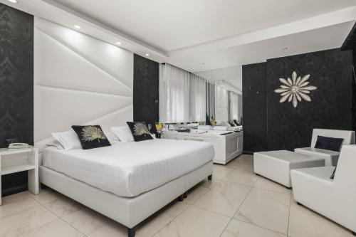 a bedroom with a large white bed and a kitchen at Reggia Suite Spa Hotel in Caserta