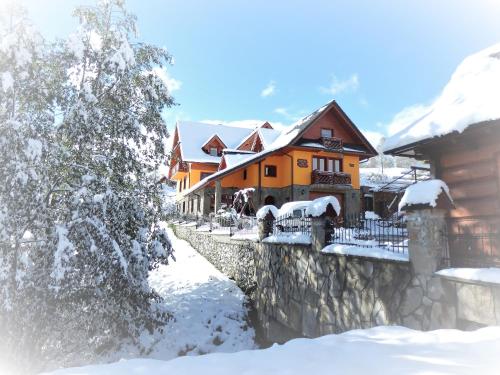 a house covered in snow next to a fence at Penzion pod Tatrami in Ždiar