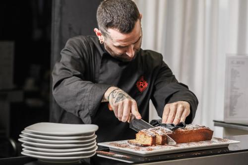 a man cutting into a cake with a knife at Reggia Suite Spa Hotel in Caserta