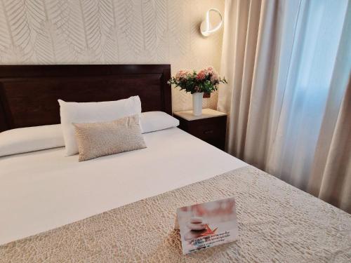 a bedroom with a bed with a book on it at Hotel Plaza Del Castillo in Málaga