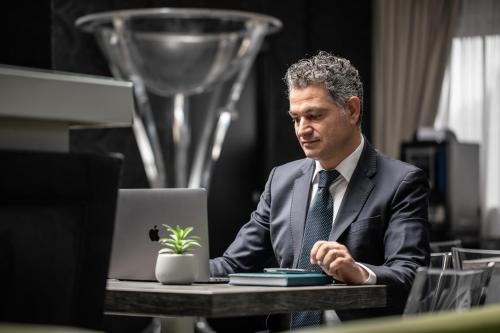 a man in a suit and tie sitting at a table with a laptop at Reggia Suite Spa Hotel in Caserta