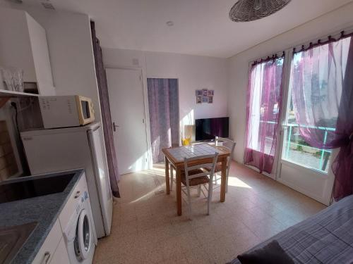 Il comprend une cuisine équipée d'une petite table et d'un réfrigérateur. dans l'établissement Appartement 1mn de la plage, à Valras-Plage