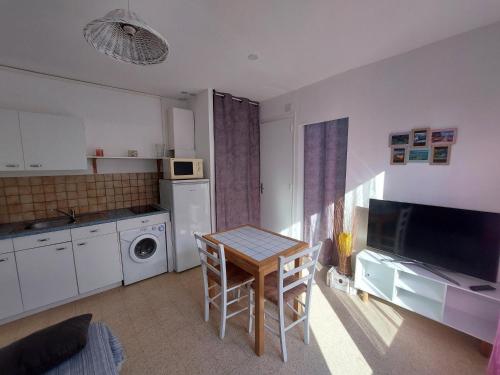 une petite cuisine avec une table et une table et des chaises dans l'établissement Appartement 1mn de la plage, à Valras-Plage