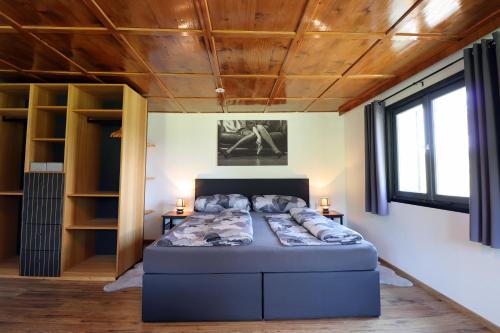 a large bed in a room with a wooden ceiling at Hus8 Krumbach in Krumbach
