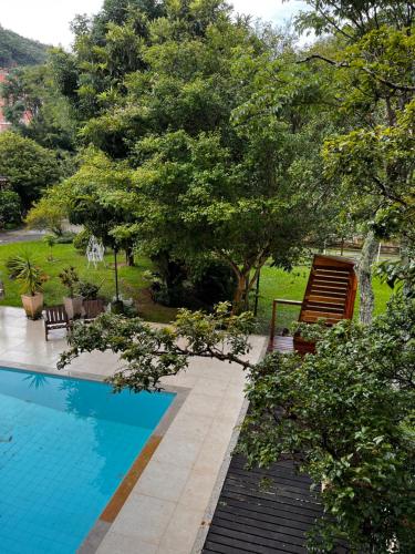 una piscina in un cortile con sedie e alberi di Villa Aconchego Corrêas Itaipava a Petrópolis