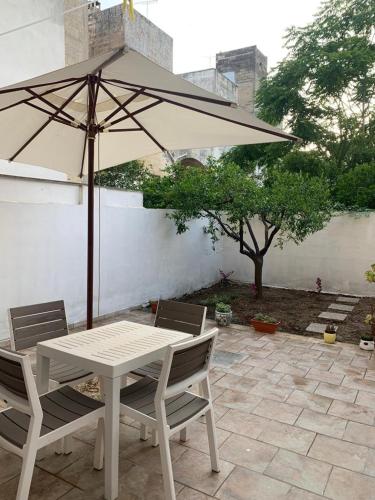 una mesa y sillas con una sombrilla en el patio en Origini - Apartment with private Garden en Lecce