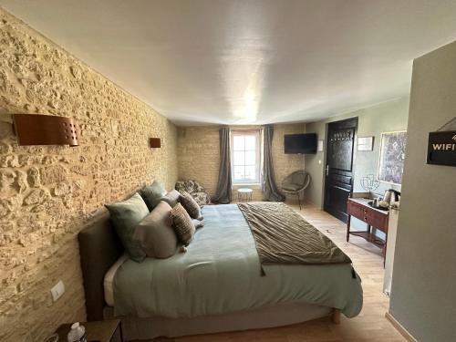 een slaapkamer met een bed en een stenen muur bij Chambres d’hôtes de l’Ancienne Auberge in Thaon