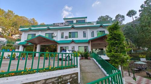 a house with a green fence in front of it at Pineland Resorts & Chalets Kasauli in Kasauli