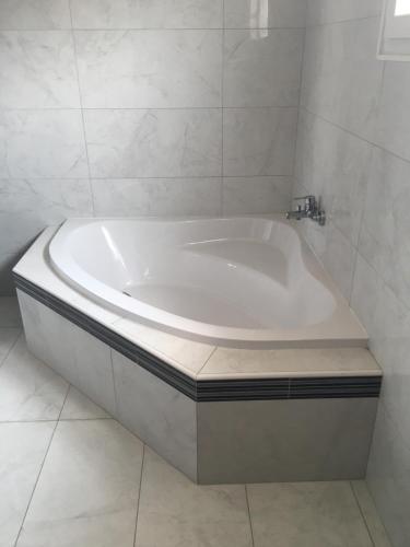 La salle de bains est pourvue d'une baignoire blanche et de carrelage blanc. dans l'établissement Chez Delphine, à Théza