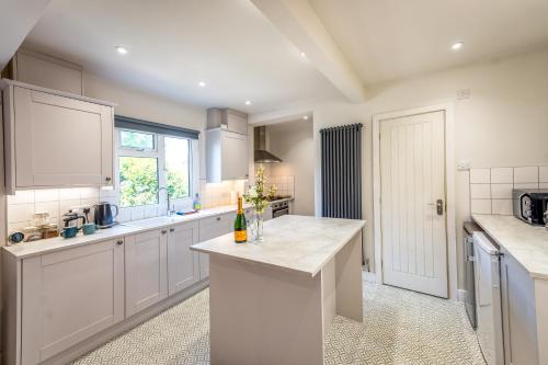 une cuisine avec des placards blancs et un comptoir dans l'établissement Pass the Keys Cosy 2 bedroom cottage in rural Shropshire, à Rodington