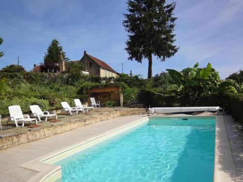 uma piscina com cadeiras brancas e uma casa em Au coeur du Périgord noir, gîte 6 pers, vue panoramique, proche Sarlat em Saint-Geniès