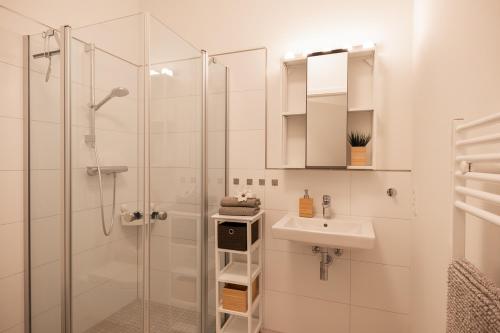 a white bathroom with a sink and a shower at Wohnen am Südstrand - Ferienwohnung 1 5 in Wyk auf Föhr