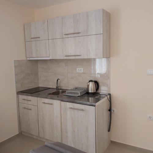a kitchen with white cabinets and a sink with a tea kettle at Villa Ronić in Soko Banja