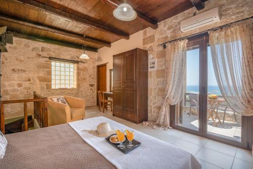 a bedroom with a bed with a table and a balcony at The Stonemade Houses in Falasarna