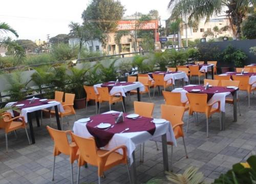 a group of tables and chairs with red and white tablecloths at Hotel Signature in Ichalkaranji