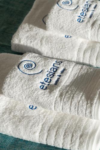 a group of white towels with blue writing on them at Etesians Suites & Villas in Super Paradise Beach