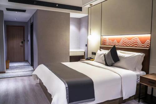 Shaoyang CountyにあるElong Leisure Hotel, Hengyang Fenghuang Road County Governmentの大きなベッドと廊下が備わるホテルルームです。