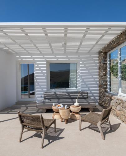 a patio with two chairs and a bench and a table at Etesians Suites & Villas in Super Paradise Beach