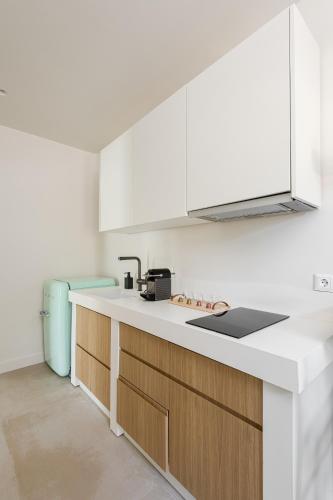 a kitchen with white cabinets and a sink at Etesians Suites & Villas in Super Paradise Beach