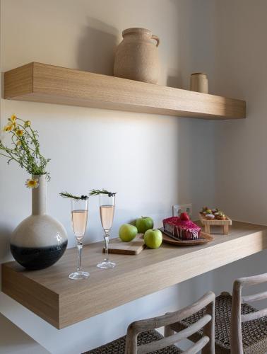 a shelf with two wine glasses and a plate of fruit at Etesians Suites & Villas in Super Paradise Beach