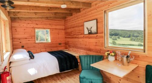 Shepherds Hut by Stepney Stays في سكرابورو: غرفة نوم بسرير وطاولة وكراسي