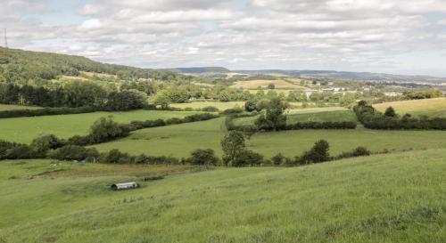 a green field with a barn in the middle of it at Shepherds Hut by Stepney Stays in Scarborough