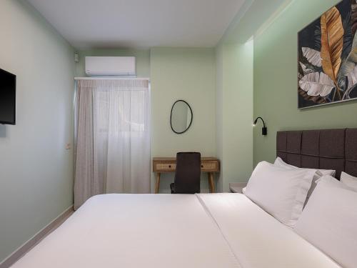 a bedroom with a large white bed and a desk at M City Hotel in Chania Town