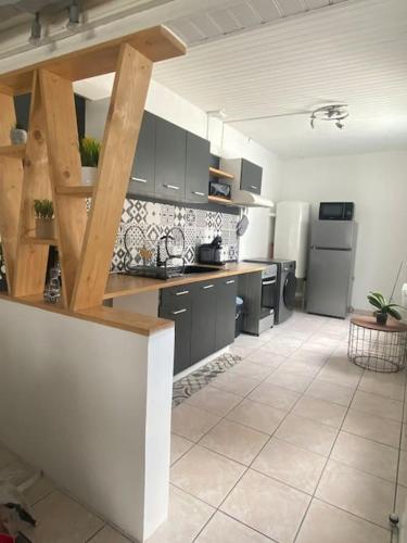 een keuken met zwarte kasten en een witte tegelvloer bij La Symphorine in Grandvilliers