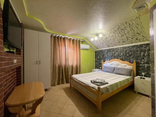 a bedroom with a bed and a tv and a table at Villa aeroport розовый дом in Chişinău