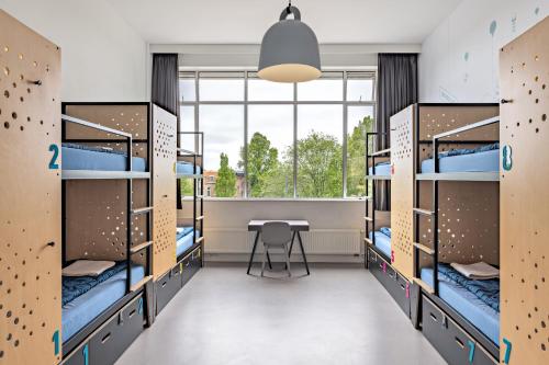 ein Zimmer mit Etagenbetten mit Tisch und Fenster in der Unterkunft Stayokay Hostel Amsterdam Oost in Amsterdam