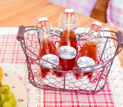 tres botellas de salsa en una canasta de alambre sobre una mesa en Zoihäusl en Hinterfirmiansreut