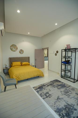 a bedroom with a yellow bed and a chair at The One chalet Oman in Bū ‘Abālī