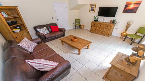 a living room with a leather couch and a coffee table at Oyster Cottage Braunton | Sleeps 6 | Dog Friendly in Braunton