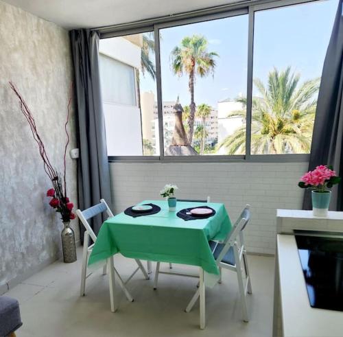 tavolo e sedie verdi in cucina con finestra di Encanto Studio a Playa del Ingles