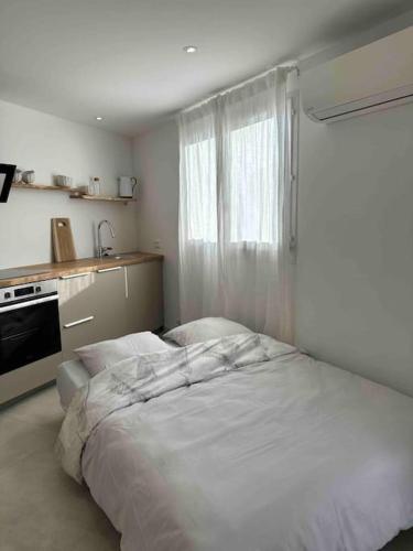 une chambre avec un grand lit blanc et une fenêtre dans l'établissement Studio à 2min à pied de la plage, à Cavalaire-sur-Mer
