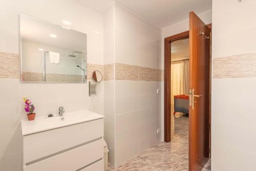 La salle de bains blanche est pourvue d'un lavabo et d'un miroir. dans l'établissement Beach Villa Can Bauza, à Port de Pollença